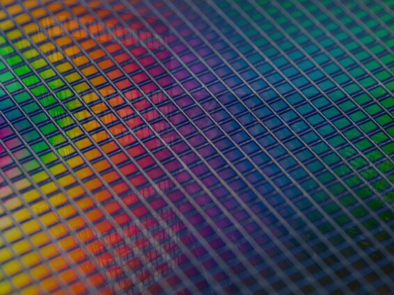 Close-up of a semiconductor wafer with a vibrant, multicolored surface pattern used in chip manufacturing.