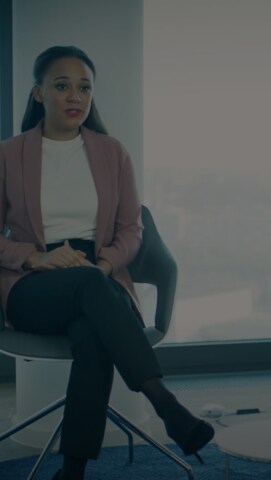 A professionally dressed woman seated in a modern office chair.