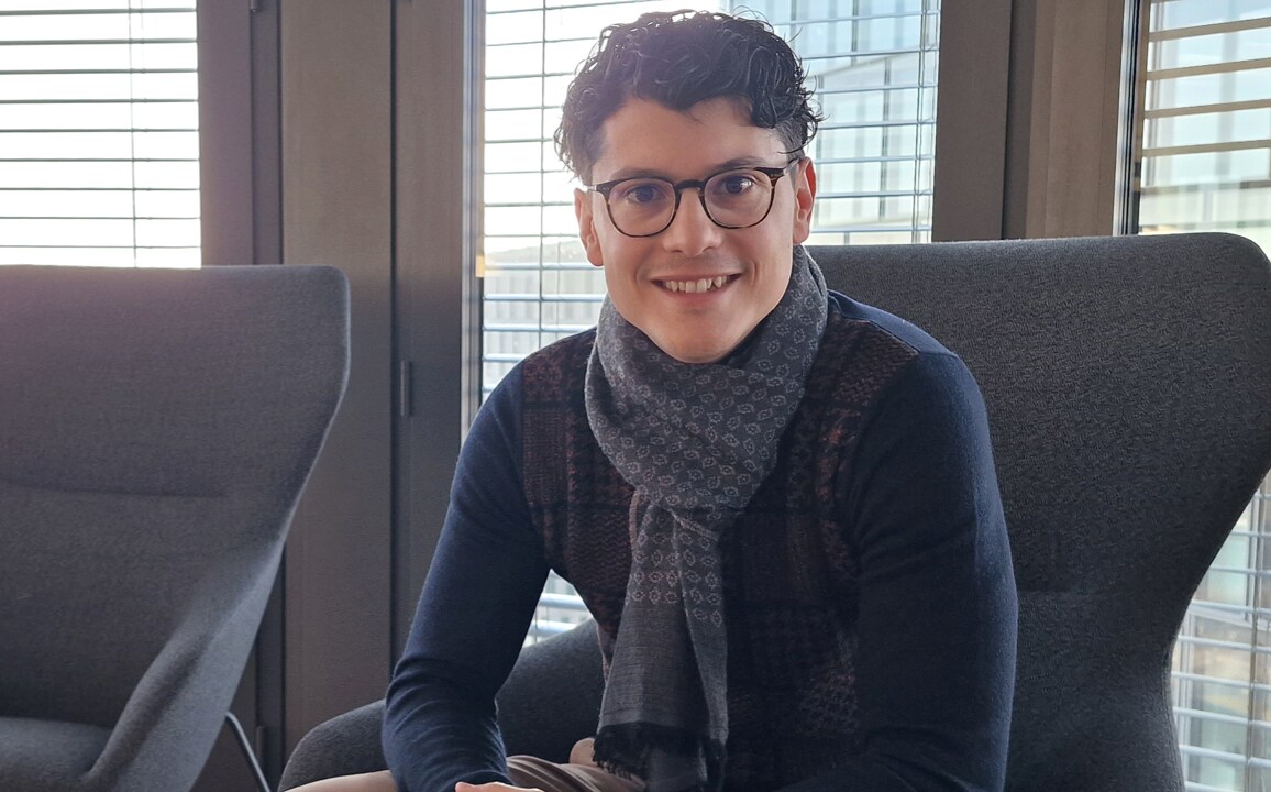 Professional portrait of Mattia Bonturi, an automotive industry account manager, seated confidently by large office windows with blinds.