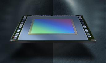 A high-tech image sensor chip, featuring a vibrant spectrum of colors on its surface, set against a glossy background.