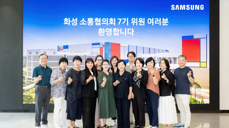 화성 삼성 캠퍼스 화면 앞에서 ‘화성 소통협의회 7기 위원 여러분 환영합니다’ 문구를 배경으로 위원들이 함께 서서 손가락 하트 포즈를 취하며 밝게 웃는 단체사진.