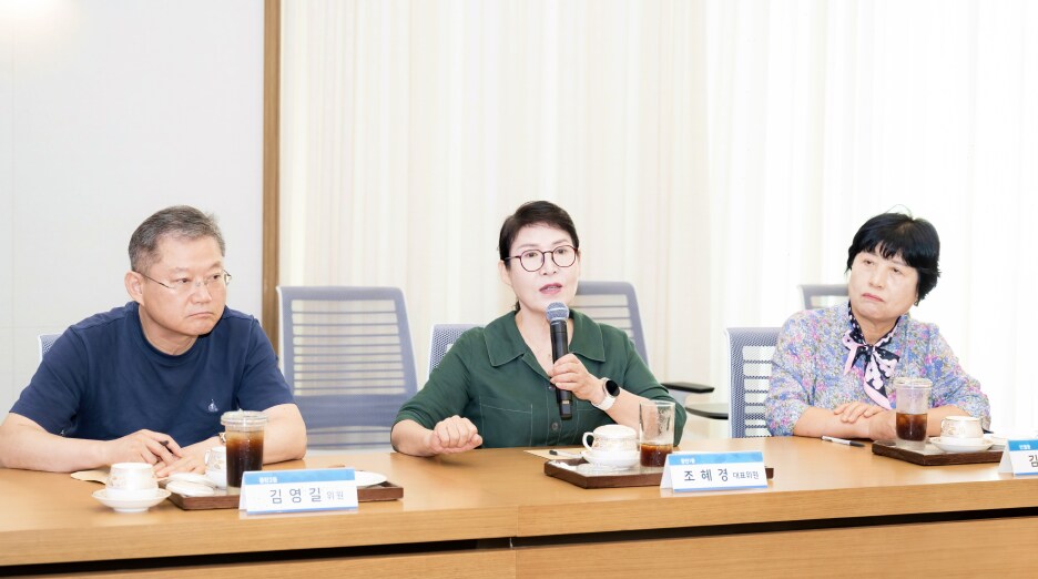 주민 의견을 전달하는 조혜경 대표 위원이 마이크를 들고 발언하는 모습, 긴 회의 테이블에 위원들이 앉아 토론에 참여하는 장면