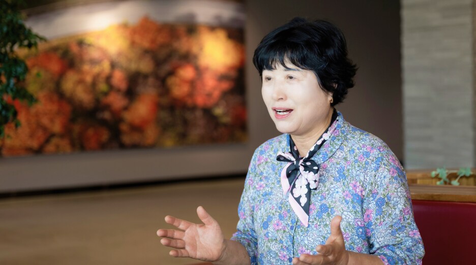 플로럴 블라우스를 입은 반월동 사회단체 협의회장 김장녹 위원이 손짓을 하며 인터뷰에서 소통의 중요성을 강조하는 모습
