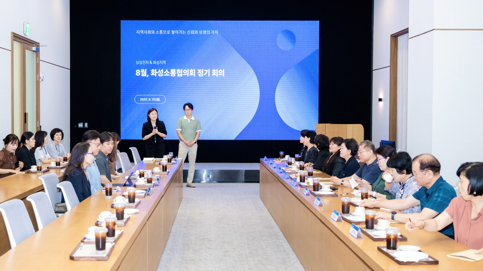 삼성전자 평택캠퍼스에서 열린 8월 화성소통협의회 정기 회의, 대형 스크린 앞에 위원들이 긴 회의 테이블 양쪽에 나란히 앉아 반도체 생산 현장 안전·환경 관리와 지역사회 소통 강화 방안을 논의하는 모습