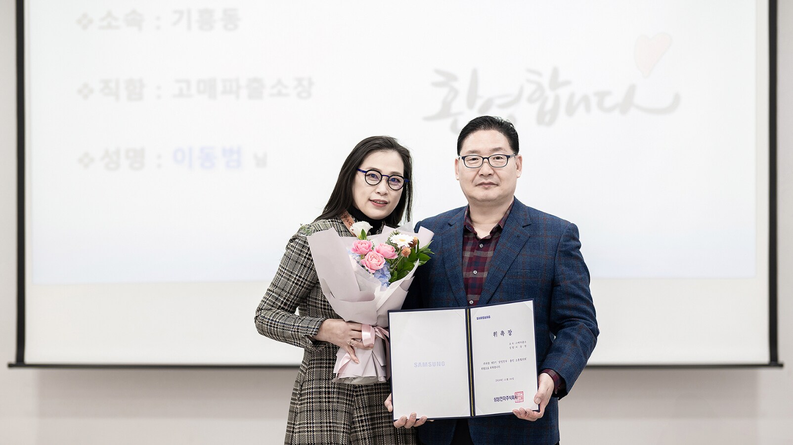 꽃다발과 위촉장을 들고 있는 고매파출소장 이동범 신임 위원과 고정미 센터장