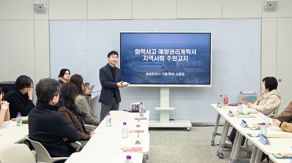 발표자가 대형 화면을 활용해 화학사고 예방관리계획서와 지역사회 고지 내용을 설명하고, 참석자들이 경청하는 회의 장면