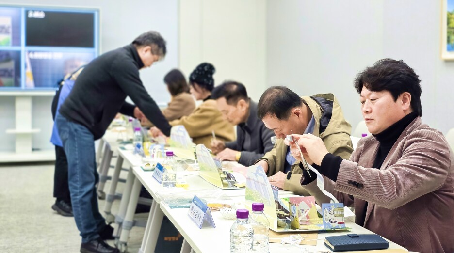 소통협의회 위원들이 책상에 둘러앉아 가위와 종이를 활용해 팝업북 제작 과정을 직접 체험하는 모습