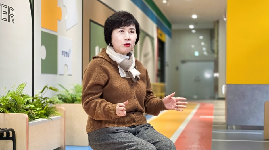 밝은 복도 공간에서 손짓을 섞어 팝업북 체험 소감을 인터뷰로 전하는 이영희 위원