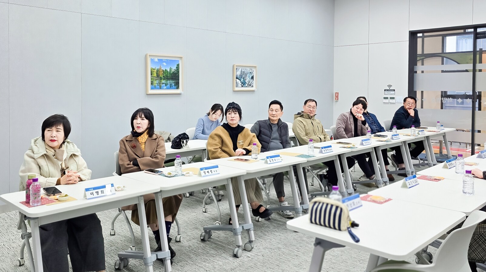 소통협의회 위원들이 양쪽 테이블에 앉아 발표를 집중해서 듣는 회의실 풍경