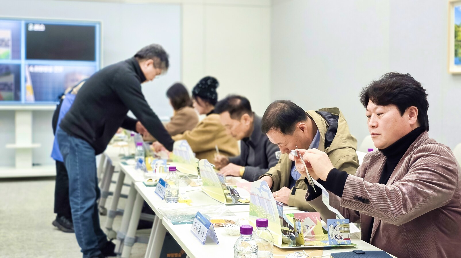 소통협의회 위원들이 책상에 둘러앉아 가위와 종이를 활용해 팝업북 제작 과정을 직접 체험하는 모습