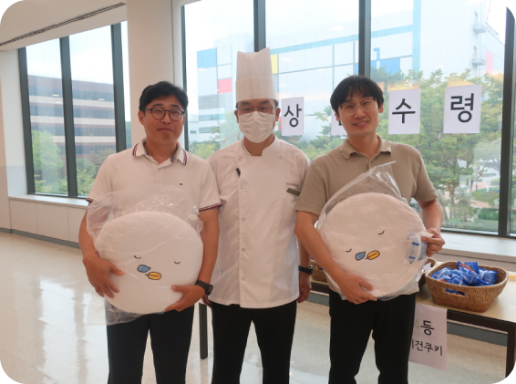 행사장에서 캐릭터 쿠션을 받은 참가자들과 셰프가 함께 기념 촬영을 하는 모습.