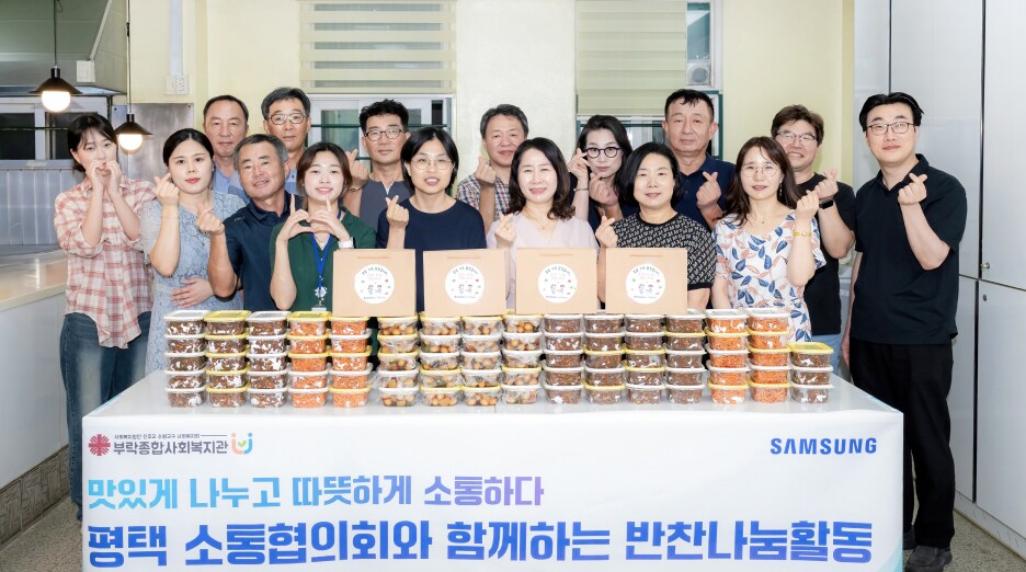 삼성 반찬 나눔 행사에서 지역 주민과 자원봉사자들이 여러 가지 반찬 세트를 준비하고 단체 사진을 찍는 모습