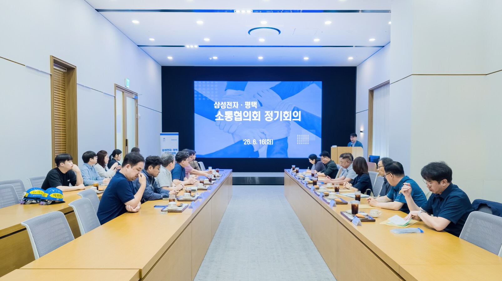 대형 스크린에 삼성전자 평택 소통협의회 정기회의 문구가 띄워진 컨퍼런스홀에서 긴 테이블 양쪽에 마주 앉아 대화를 나누는 위원들