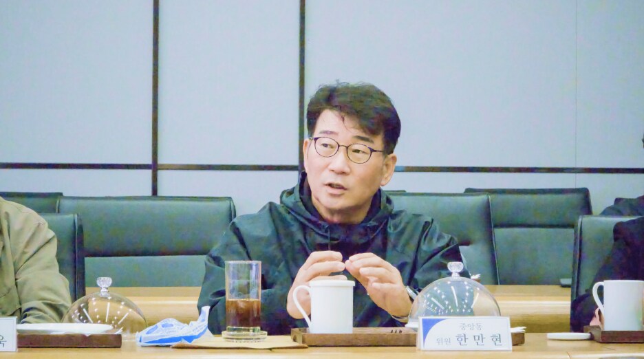 중앙동 한만현 위원이 회의 중 화학물질 예방관리 관련 주제에 대해 발언하고 있다. 앞에는 음료와 자료가 놓여 있다.