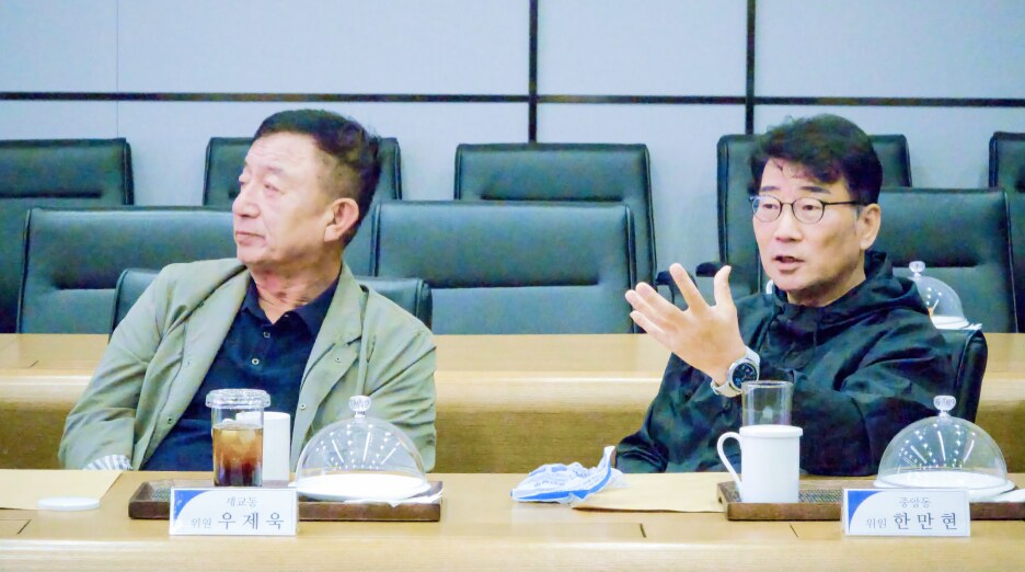 우제욱 대표위원(왼쪽)과 한만현 위원(오른쪽)이 분동 관련 사안에 대해 의견을 나누며 진지하게 대화하고 있다. 테이블 위에는 음료와 자료가 정돈되어 있다.