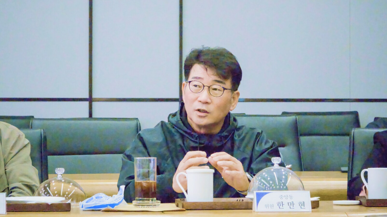 중앙동 한만현 위원이 회의 중 화학물질 예방관리 관련 주제에 대해 발언하고 있다. 앞에는 음료와 자료가 놓여 있다.