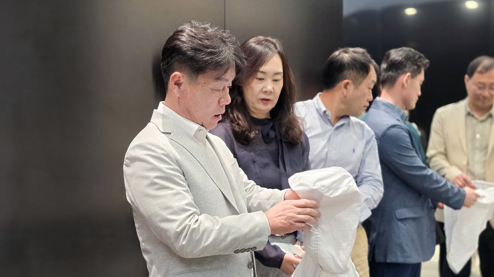 플라스틱을 재활용하여 제작된 방진복을 직접 만져보고 있는 정문환 대표위원