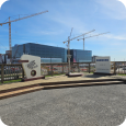 The Samsung Taylor site with a 'Welcome to Taylor Texas' sign in the foreground and cranes towering over a large building in the background. 