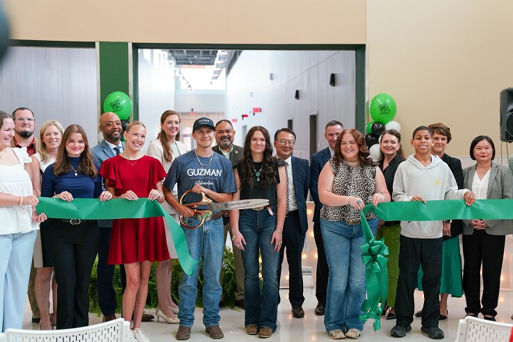Students and representatives cutting a green ribbon