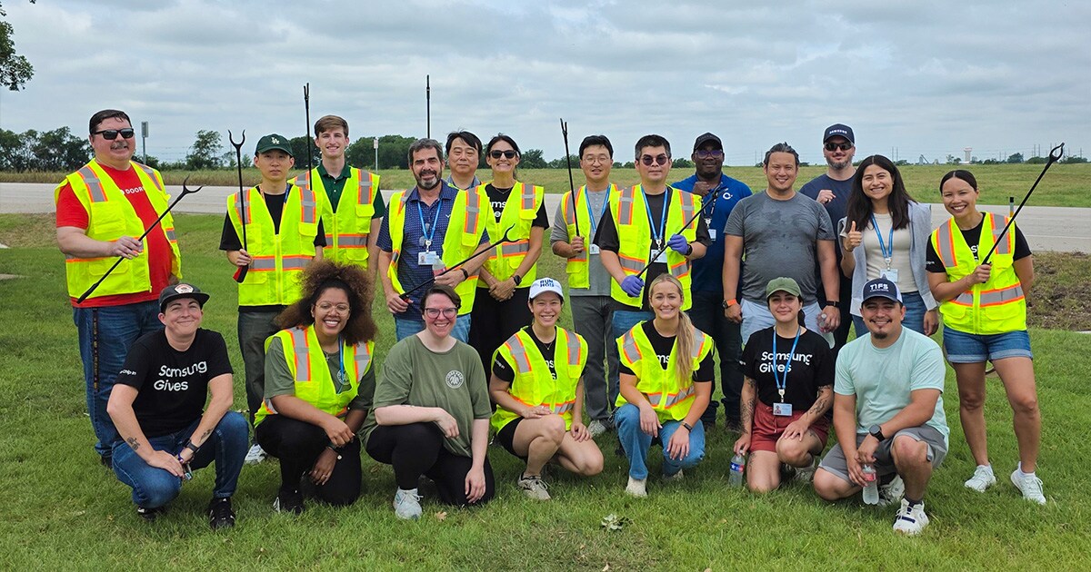Employees gather for a group photo during a community cleanup volunteer activity in a local outdoor area.