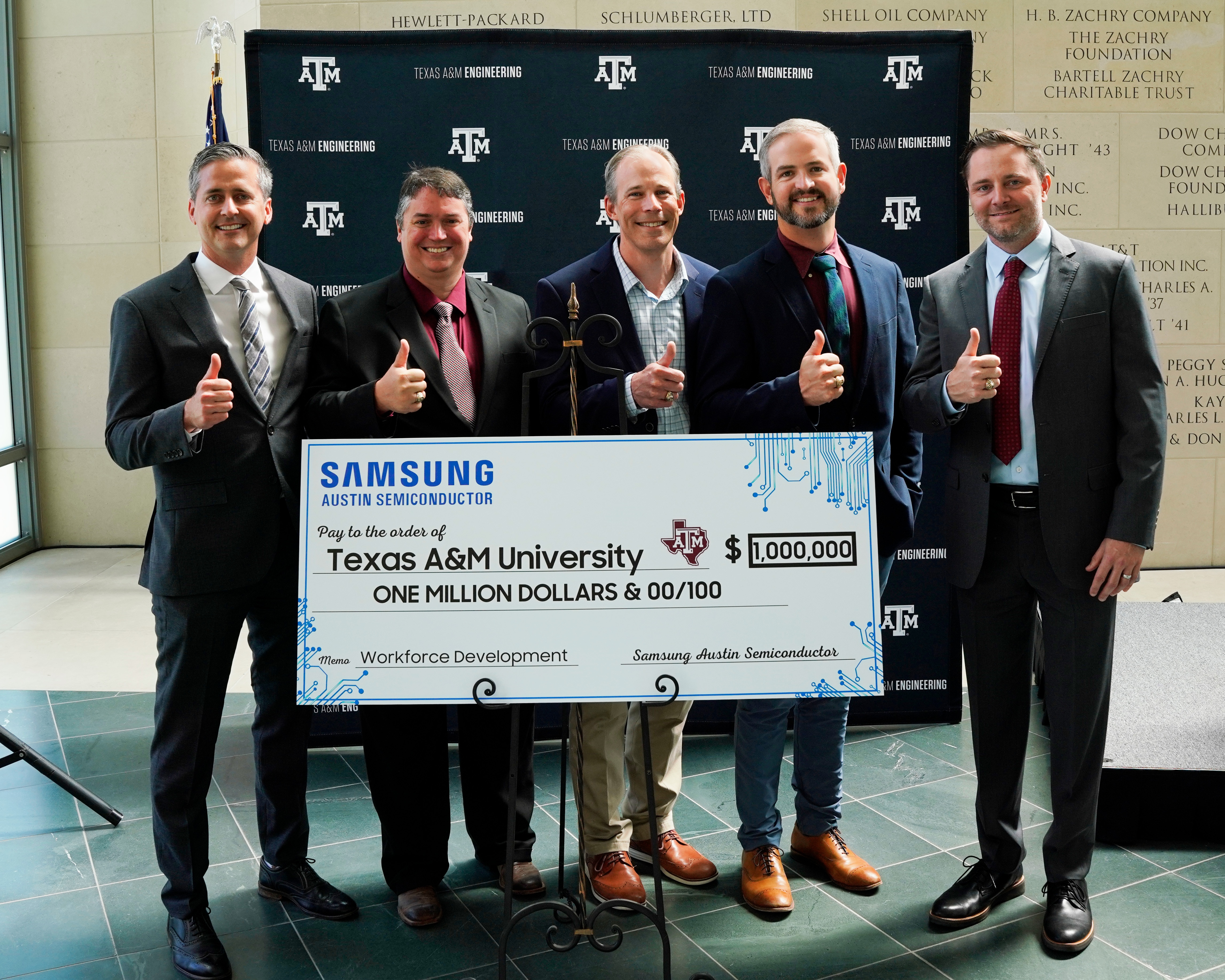 Five individuals who are Samsung Austin Semiconductor employees graduated from Texas A&M University posing with a ceremonial check 