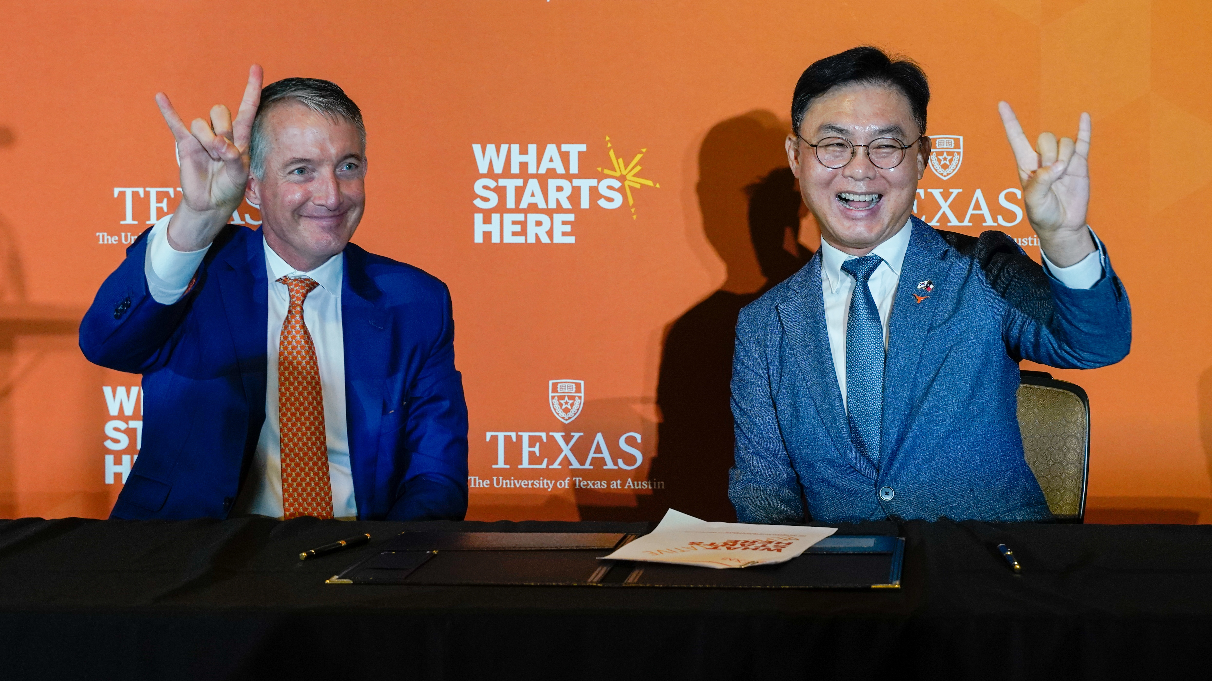 The University of Texas at Austin president Jay Hartzell, left, and Samsung Austin Semiconductor president Bonyoung Koo, give the Hook ‘Em Horns gesture at Samsung Austin Semiconductor’s donation announcement on Sept. 1, 2023