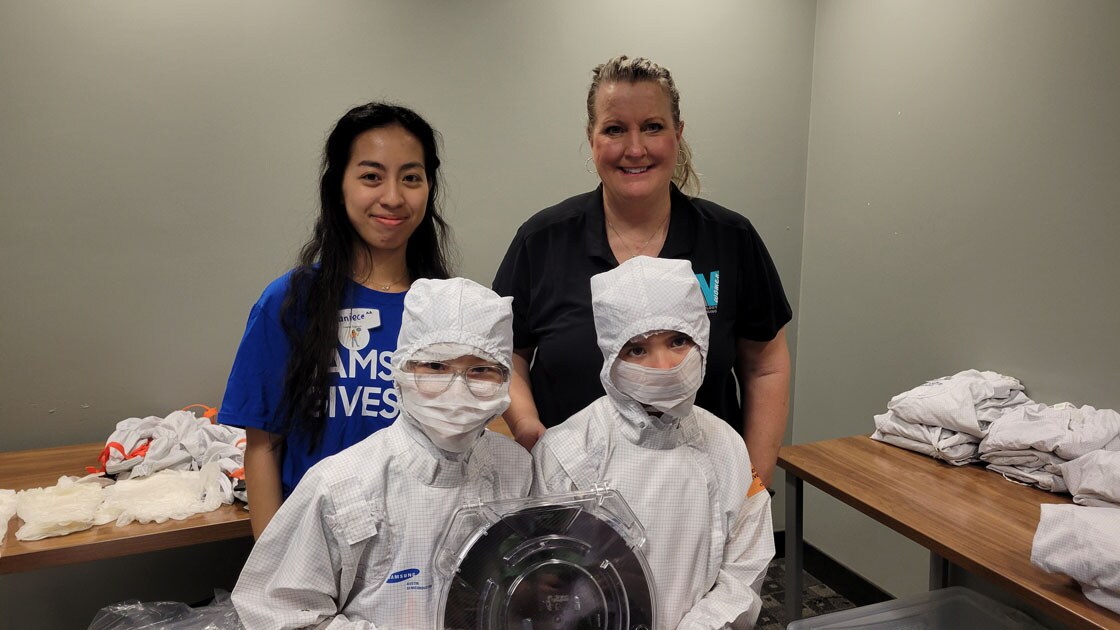 Samsung Austin Semiconductor employees posting with students dressed up in cleanroom suits.
