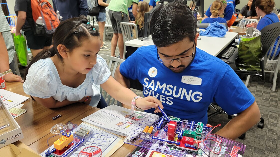Samsung Austin Semiconductor employee helping a student with circuits.