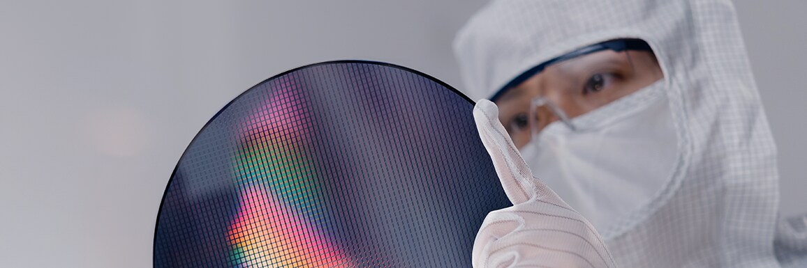 A cleanroom engineer carefully inspecting a silicon wafer.