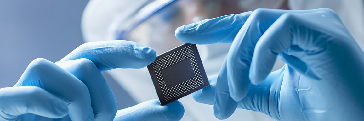 A close-up image of a gloved professional holding a microchip.