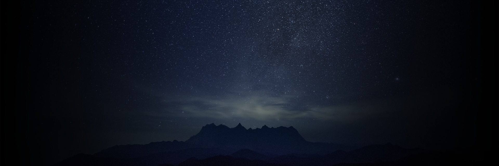 星空の下に山脈がシルエットになっている静かな夜の風景です