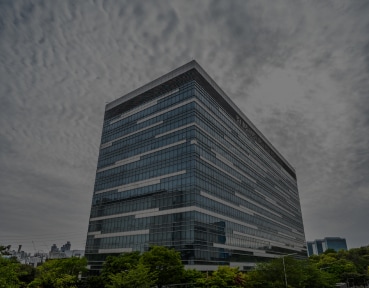 Aerial view of a Samsung office building in Korea, featuring a sleek, horizontal glass façade and a rooftop garden amidst an urban landscape.