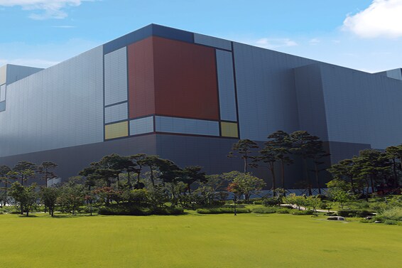 サムスン半導体製造工場の広角ビュー。外観はモダンなカラーブロックで、前面は緑の造園が施されています。