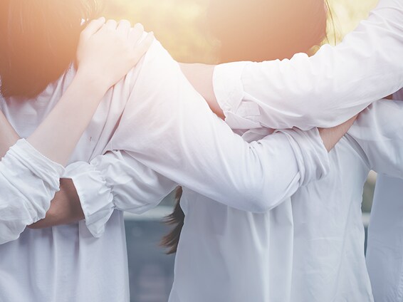 A close-up of three people standing shoulder to shoulder in white shirts.