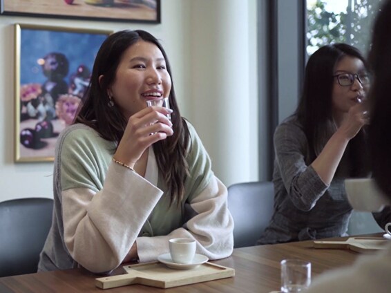 Two women enjoying coffee and conversation at a modern café-style table.