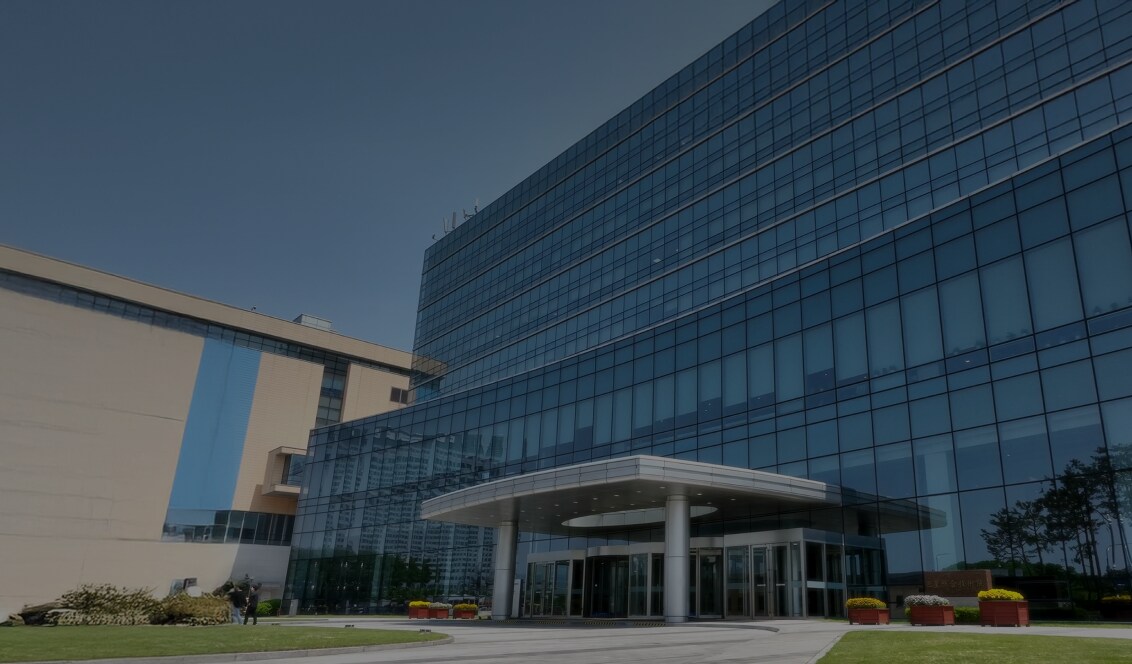 A modern Samsung office building with a sleek glass façade and a prominent main entrance, set against a clear blue sky.