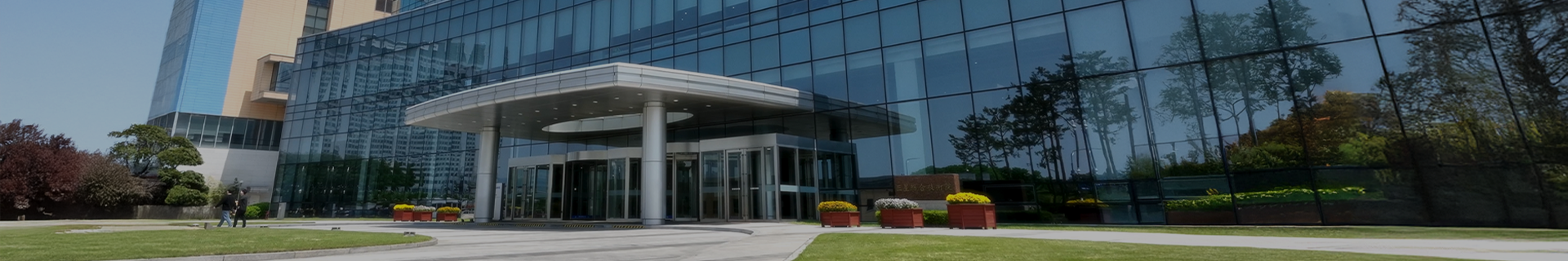 A modern glass-fronted corporate building with a circular entrance canopy
