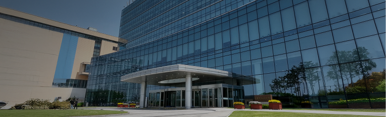 A modern glass-fronted corporate building with a circular entrance canopy