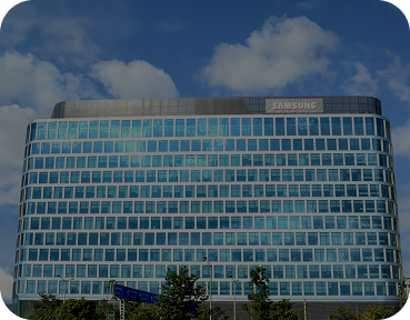 Front view of the Samsung office building with a sleek grid of reflective windows under a partly cloudy sky.