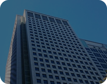 Low-angle view of a tall corporate building with a grid of uniform windows against a clear blue sky.