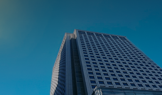 A low-angle view of a modern office skyscraper in Japan with grid-like windows and a clear blue sky in the background.