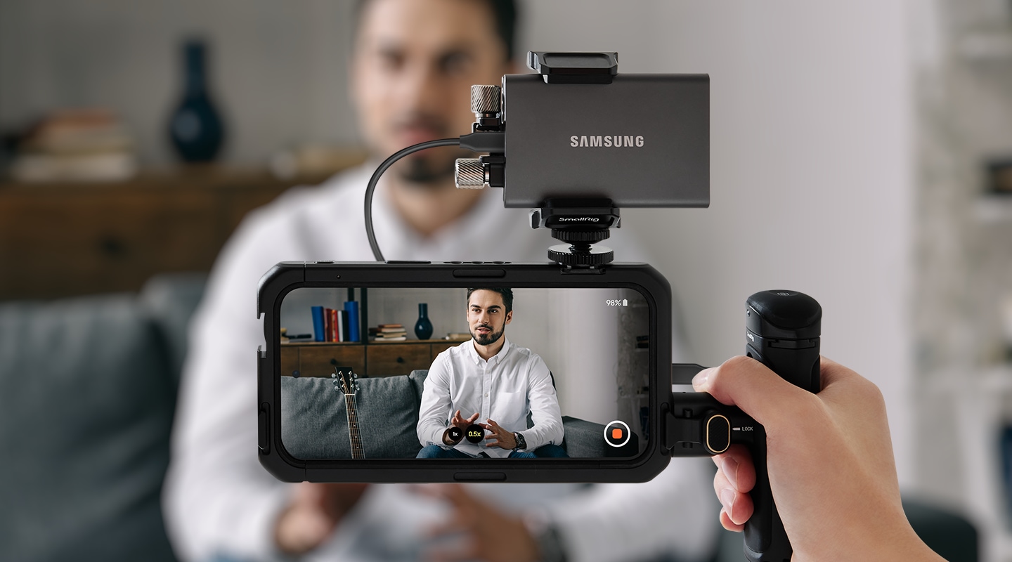 Samsung ポータブル SSD T7が接続されたスマートフォンを使用した動画撮影セットアップで、室内の人物を記録しています。