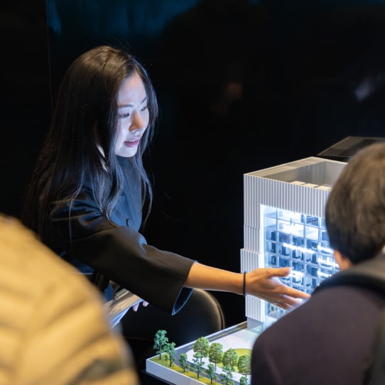 A Samsung employee gestures toward a lit architectural model at CES 2025.