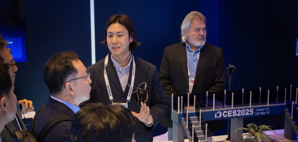 Attendees gather around a Samsung expert explaining an advanced mobility and infrastructure concept.