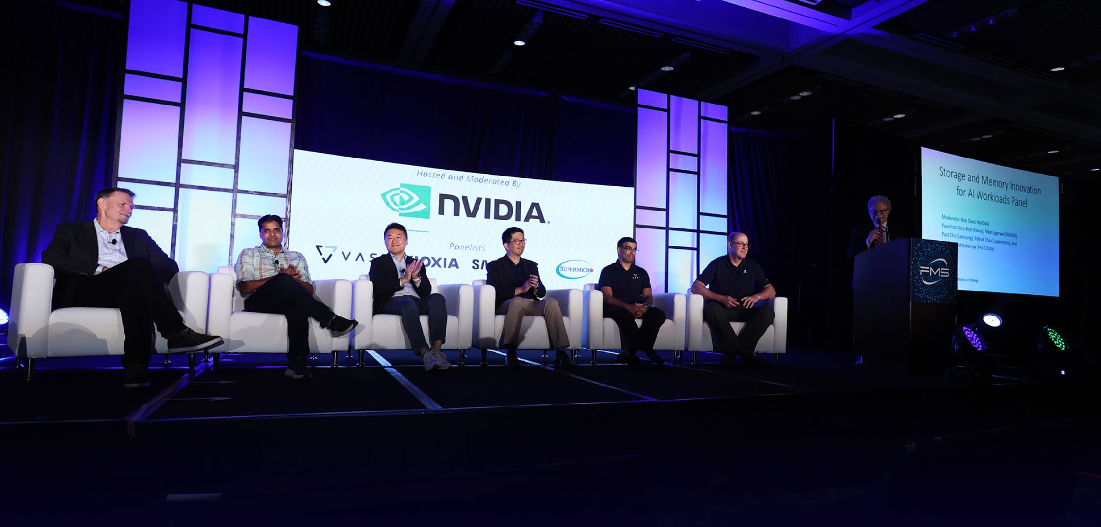 A panel of six speakers seated on stage at FMS 2024, with a large screen behind them displaying the NVIDIA logo.