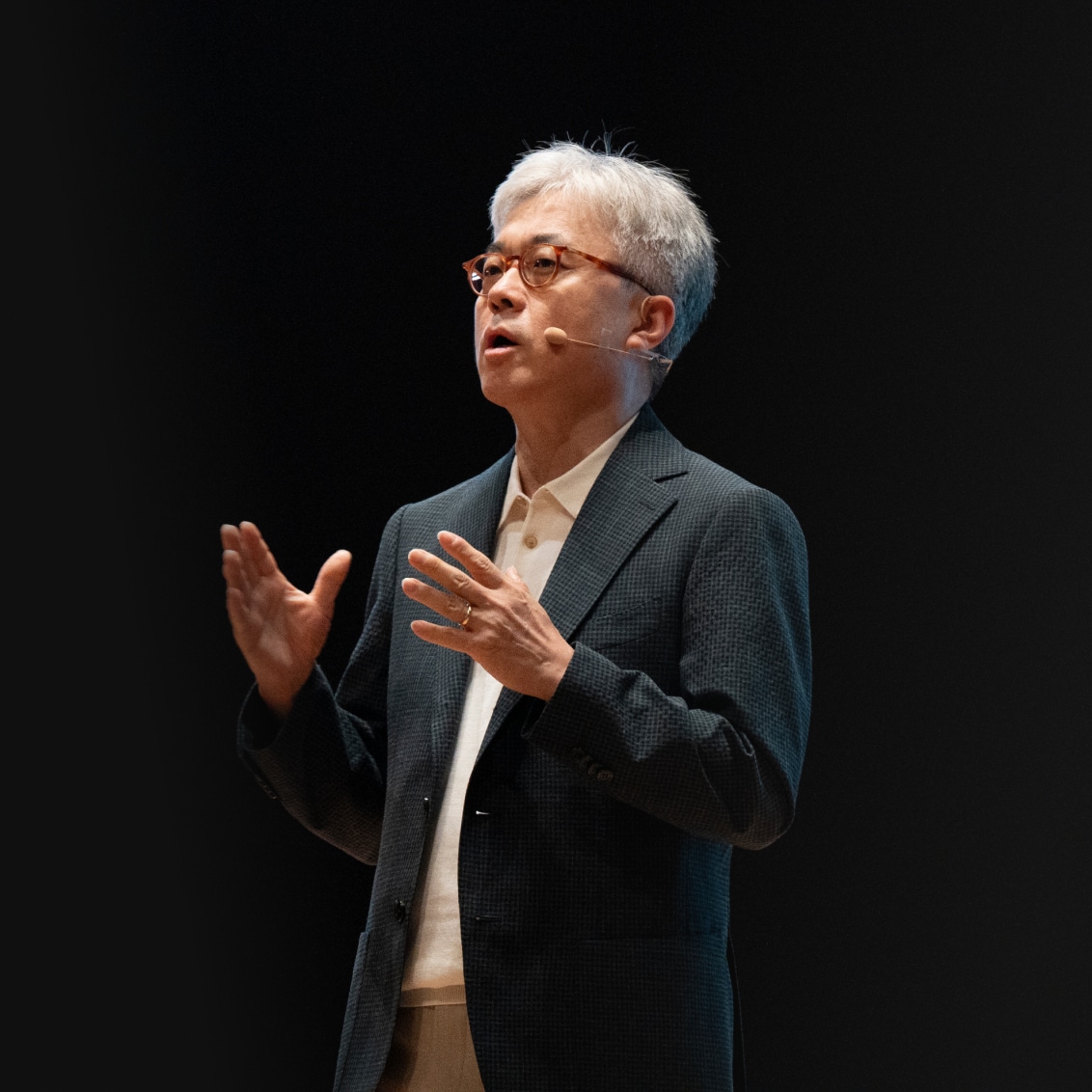 A speaker in a suit, gesturing with his hands while speaking at Samsung Foundry Forum 2024, with the text Foundry illuminated behind him.