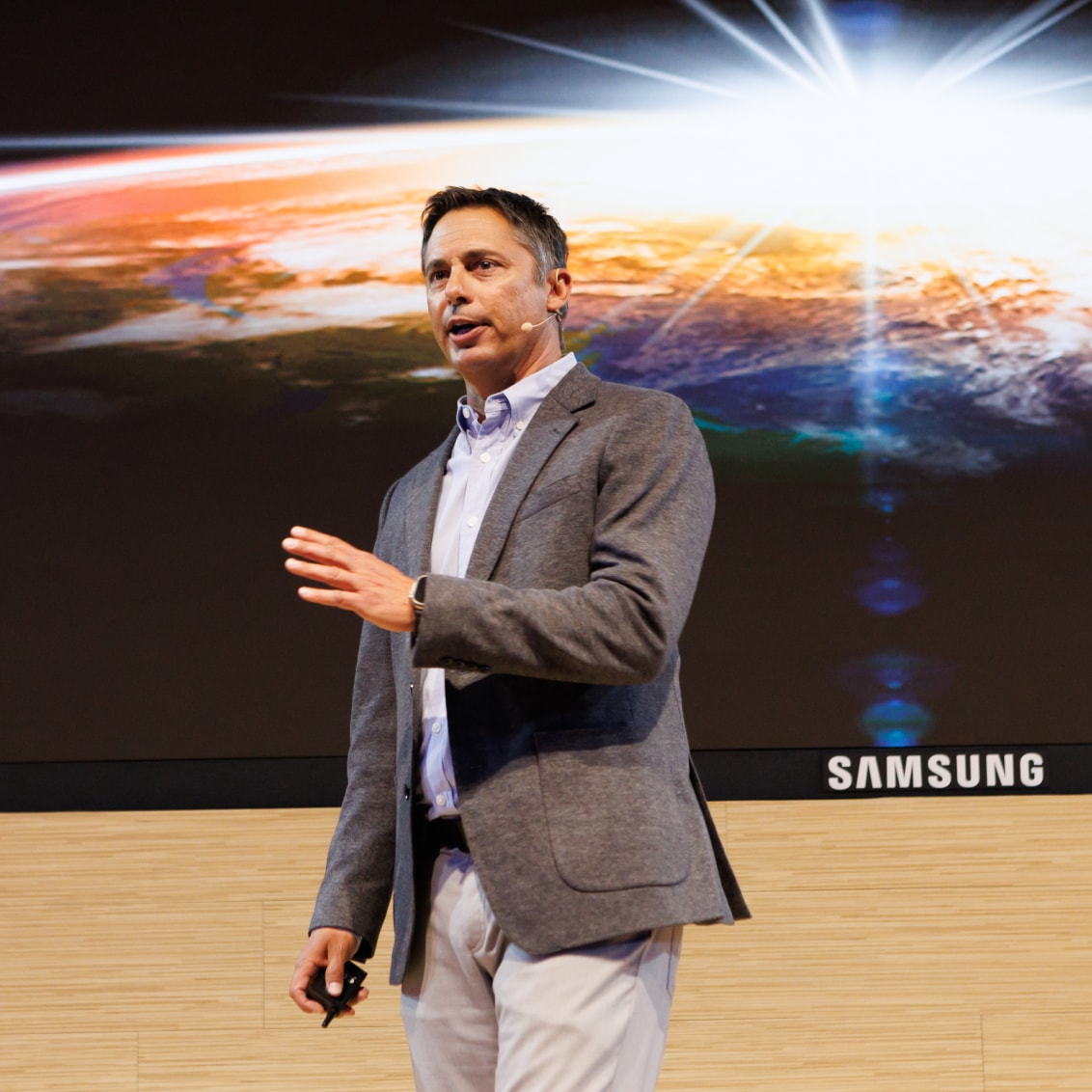 A man in formal attire presenting on a stage