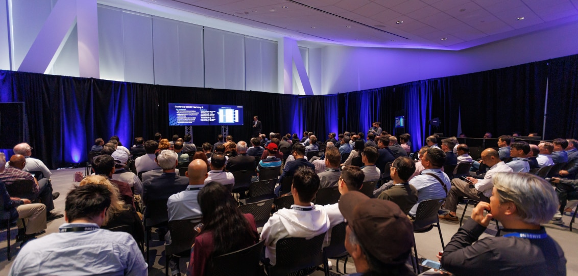 A forum in progress, with a crowd seated and focused on a technical presentation