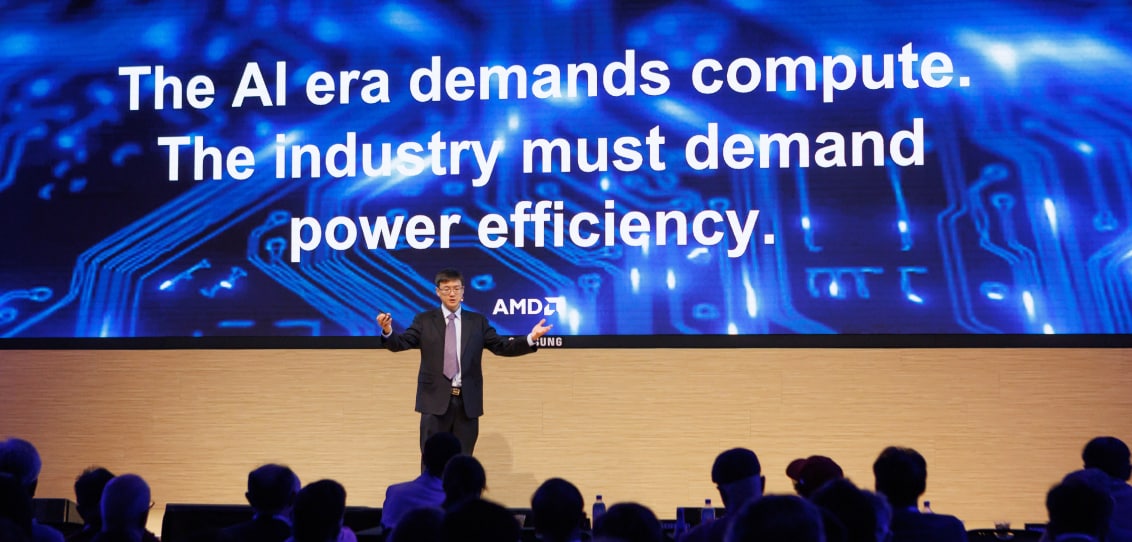 A presenter in formal attire emphasizing the importance of compute and energy efficiency in the AI era, with an engaged audience