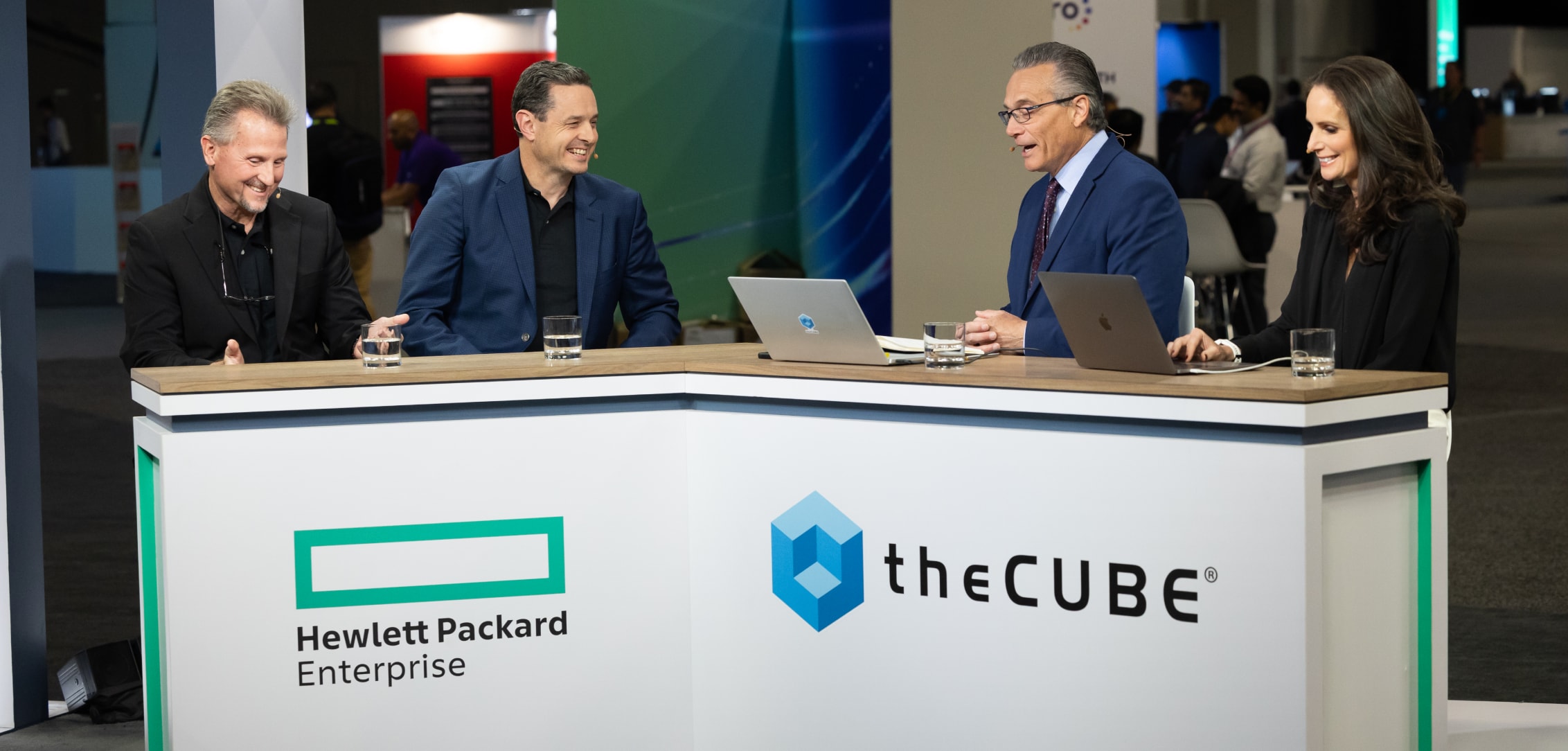 Four professionals engaging in a lively discussion at the Hewlett Packard Enterprise and theCUBE broadcast booth during HPE Discover 2024.
